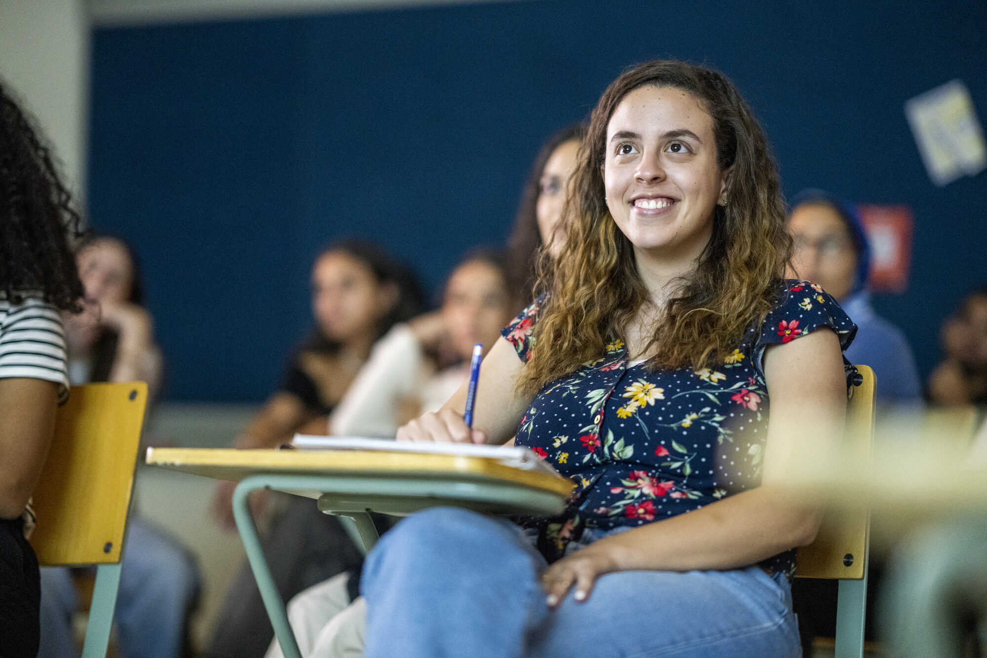 smiling female student in classroom attentive to lecture