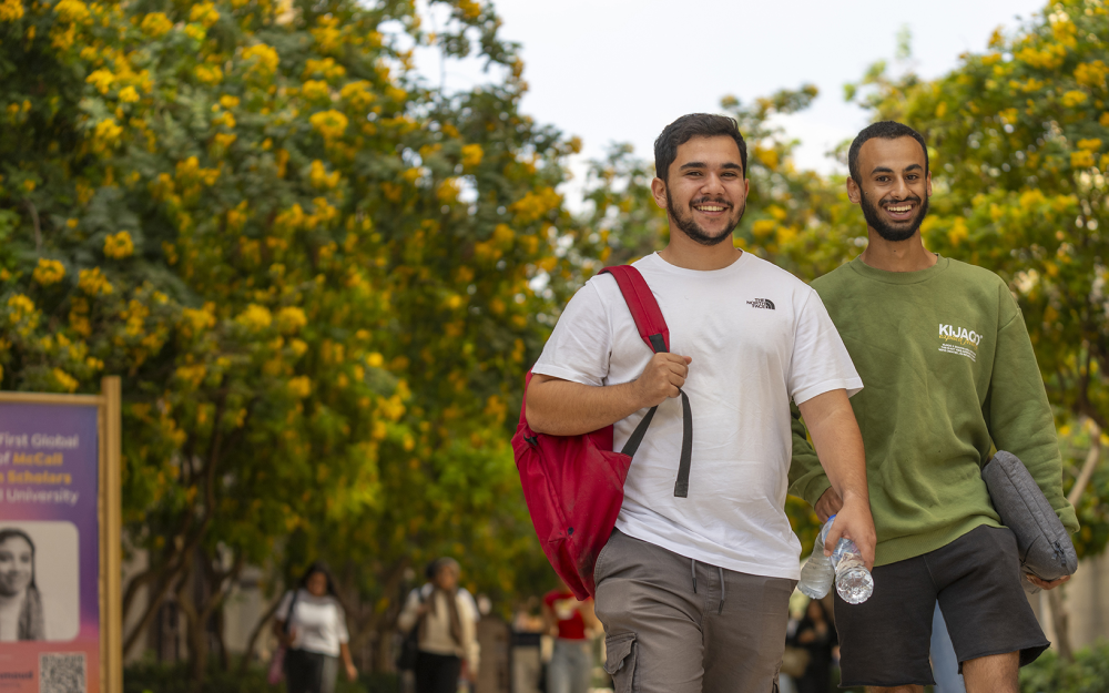 male students smiling walking on campus to their classrooms