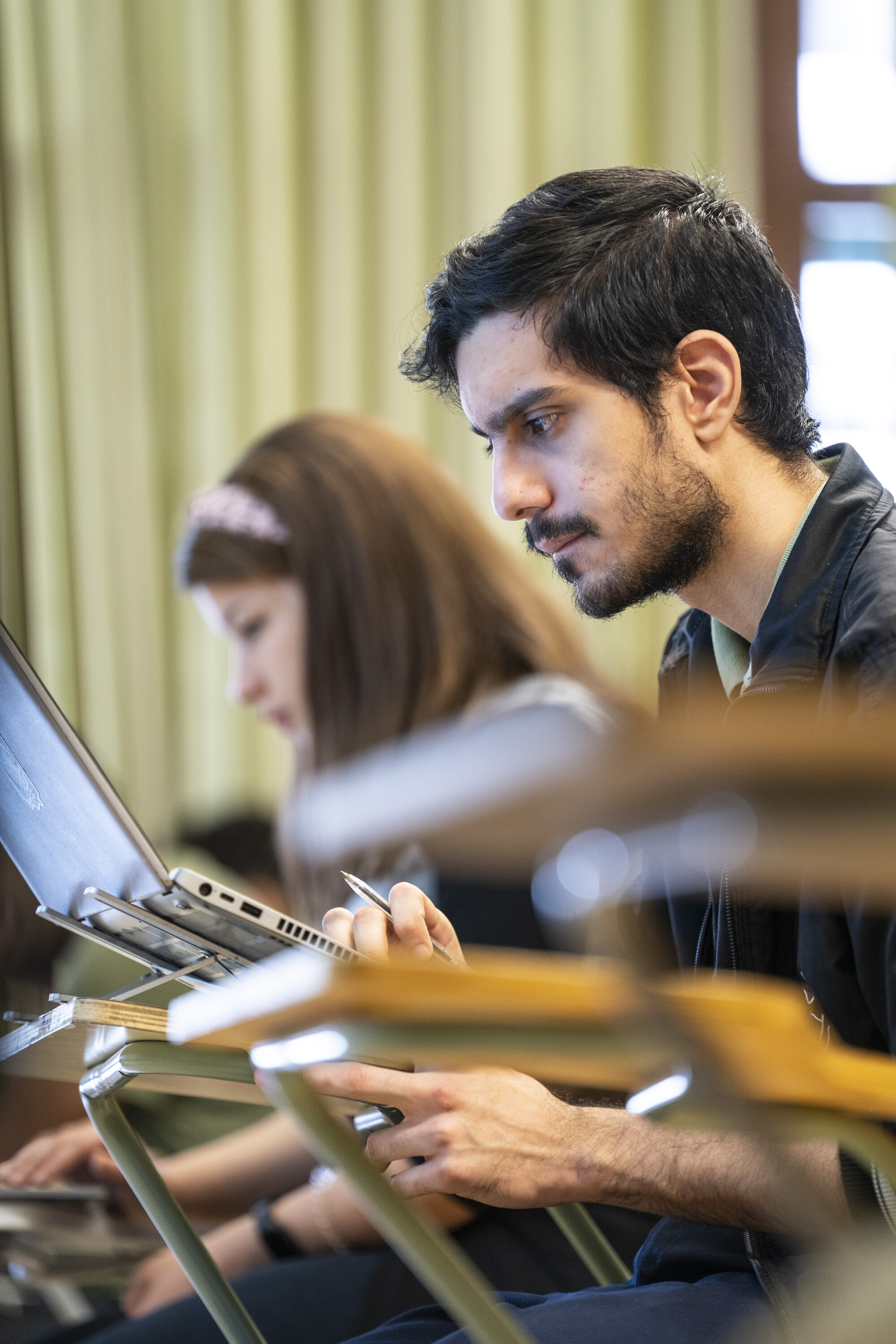 student concentrating in class taking notes on laptop