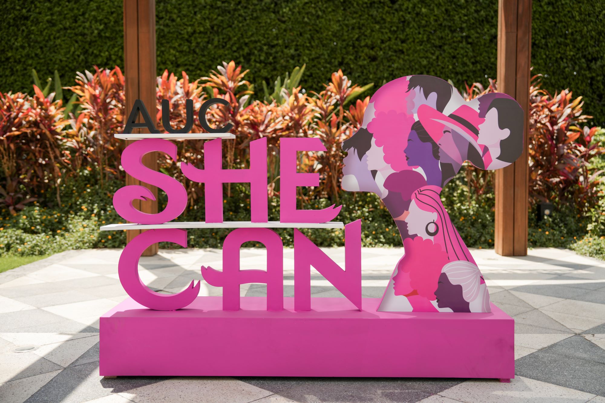 A wooden backdrop for she can logo and title