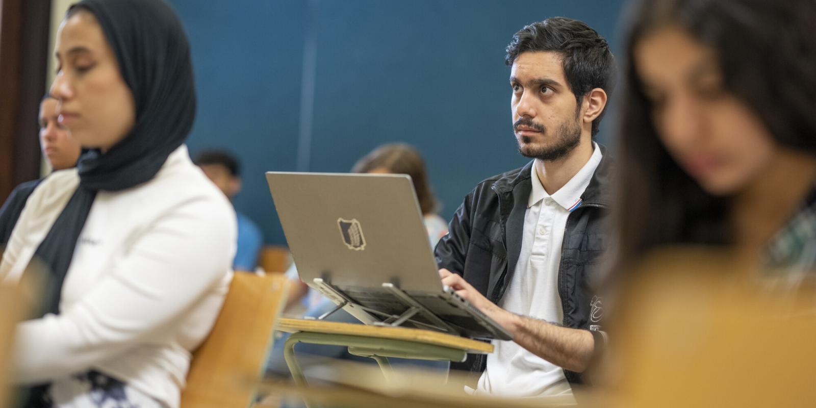 male student in class taking notes