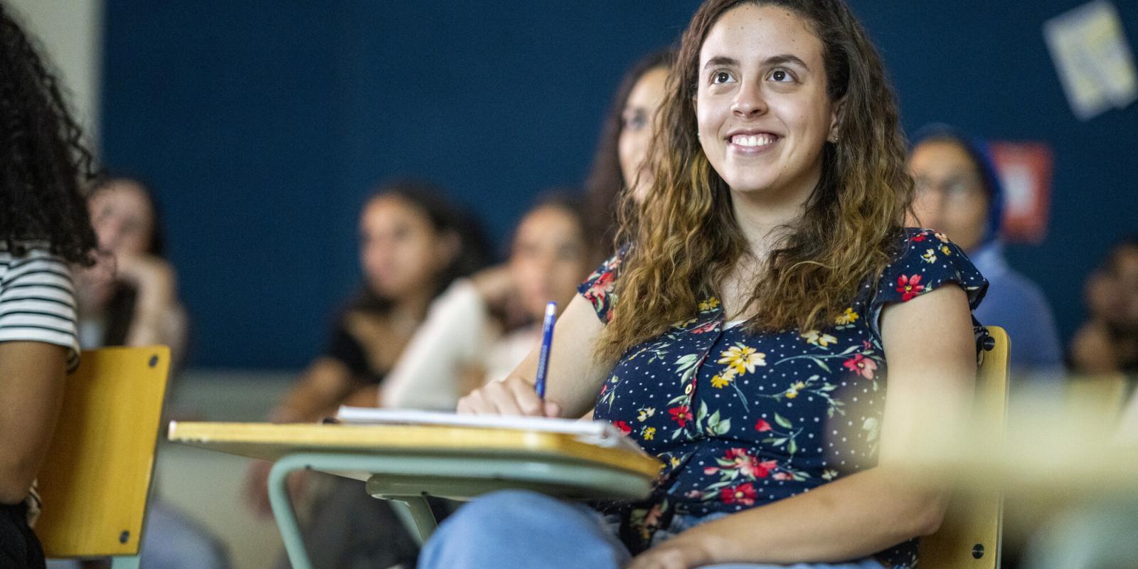 smiling female student in classroom attentive to lecture