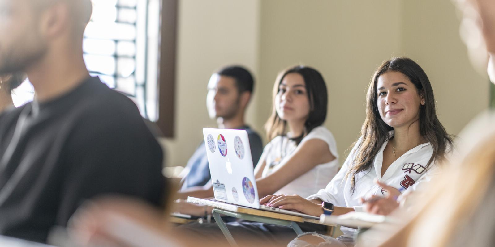 student in class room taking notes on laptop