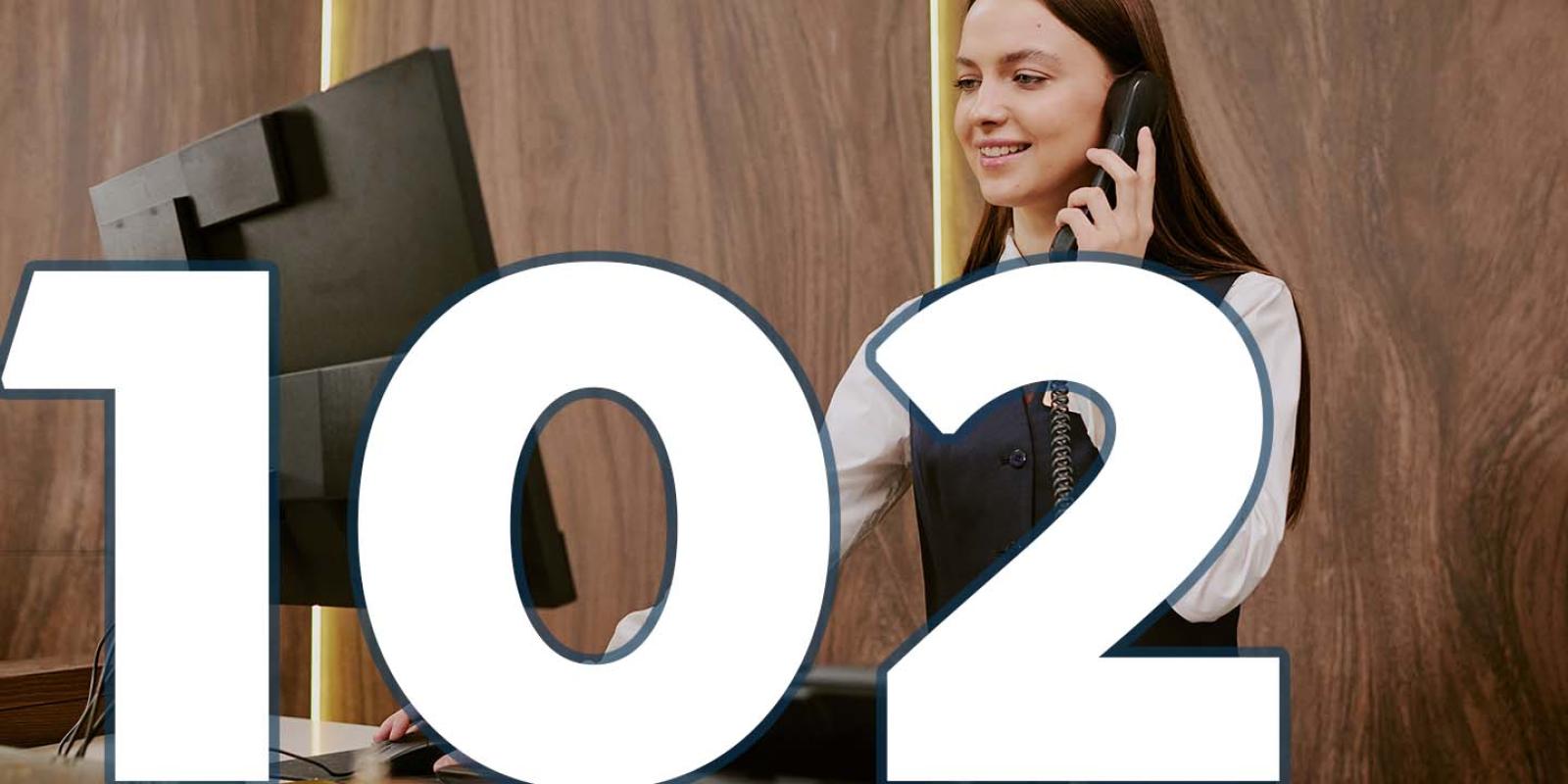 A receptionist is talking on the phone and looking into a screen. Text: 102