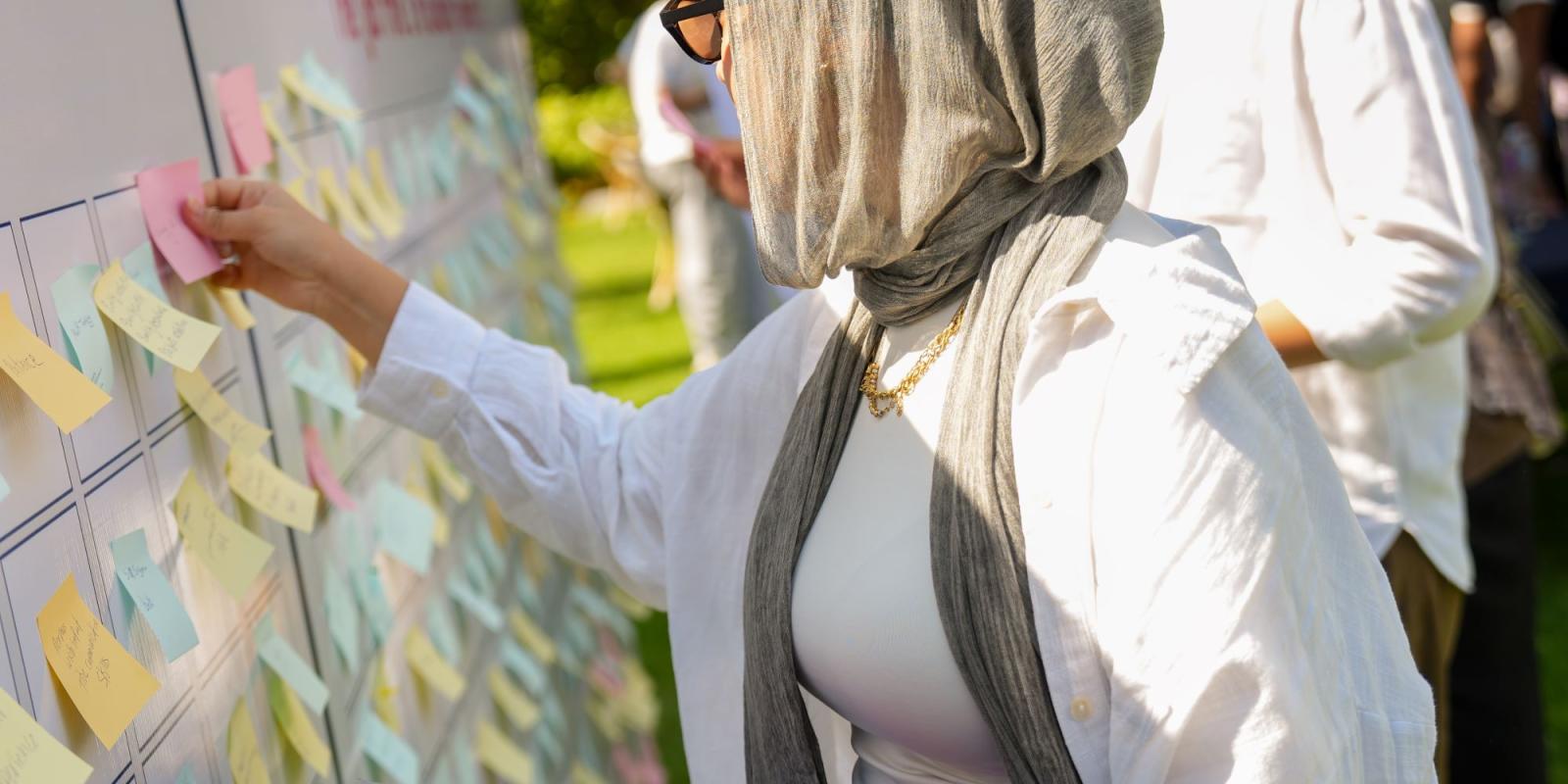 Attendee is sticking what is her most needed skill on a large wooden backdrop