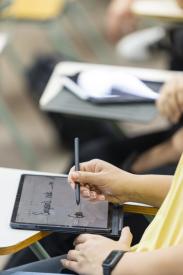 students writing notes in classroom on tablet