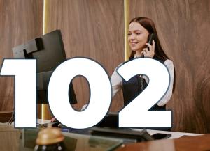 A receptionist is talking on the phone and looking into a screen. Text: 102