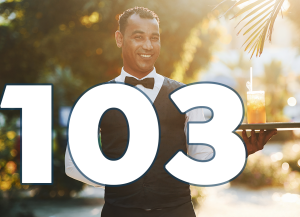 A waiter is holding a tray. There is a glass of juice on it. Text 103